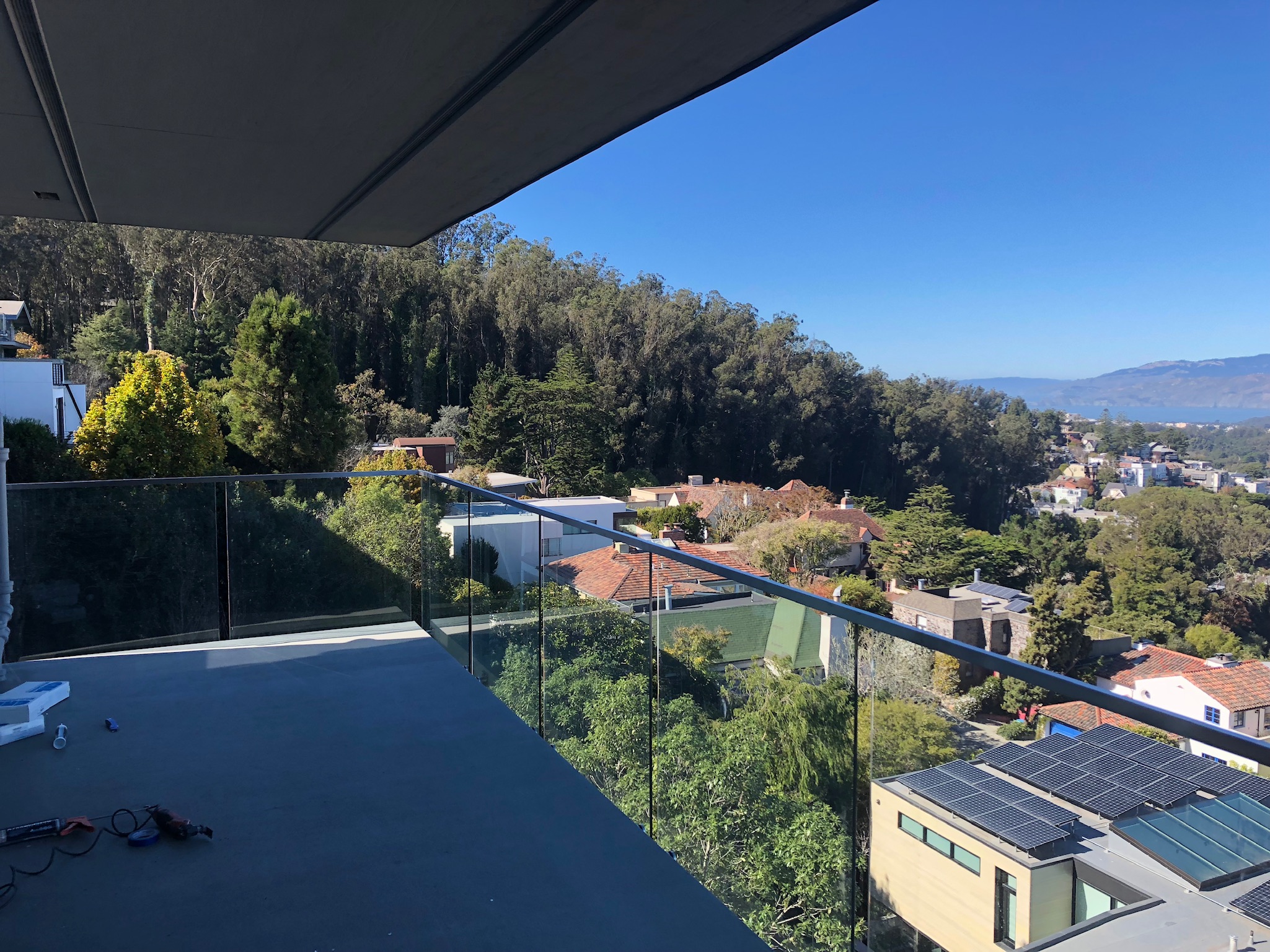 Completed rooftop deck with frameless glass guardrail overlooking San Francisco